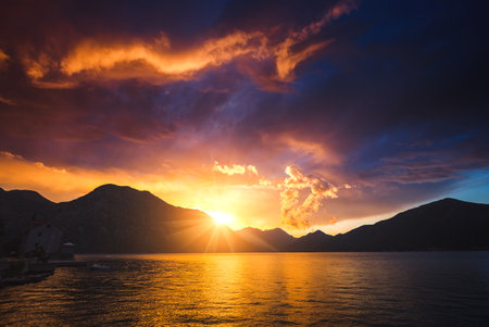 Bright red clouds illuminated by the sun, dark ominous sky. Location place Kotor bay, Montenegro, Adriatic sea, Europe. Dramatic light in summer weather. photo wallpaper. Discover the world of beauty.の写真素材