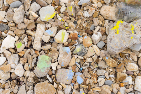 Pebbles with colored paint and crayons lying on a beachの写真素材