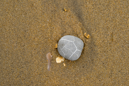 Gray stone with white lines lying on a sand beach.の写真素材