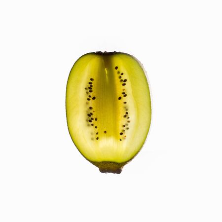 Slice of kiwi fruit with light shining through backlight showing the structure and details isolated on a white backgroundの写真素材