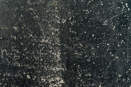an empty background of black concrete that is worn down or weathered and showing texture with copy...