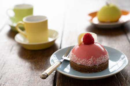 Two Small French ball shaped cakes mousse dome served on a plate with cups of teaの写真素材