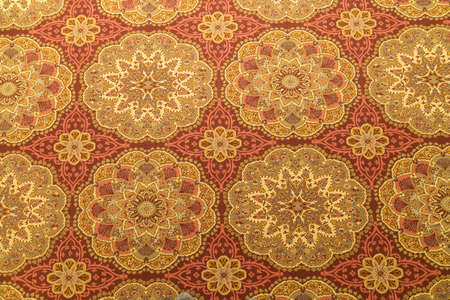 a Close up of a detail or a fug or tapestry on the floor in yellow and orange and gold with circular...
