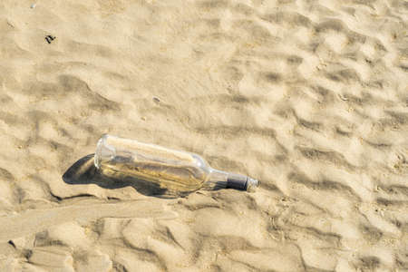 a Junk glass wine bottle on sand beach in the sun, concept of sea or oceanic wasteの写真素材