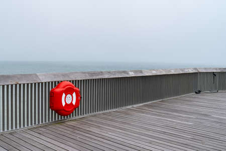 Wooden structure of the Pier of Hastings, East Sussex, England with a red lifebelt lifesaver on a day with sea mist in summer 2018の写真素材