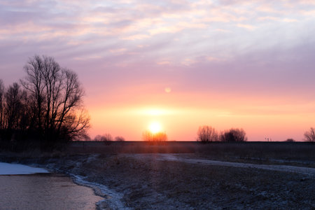 Sunrise with a red and yellow colored sky with frozen landscape, ice and clouds in the winterの写真素材