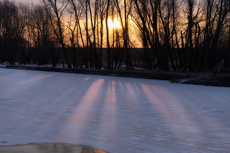 Sunrise with a red and yellow colored sky with frozen landscape, ice and clouds in the winterの写真素材
