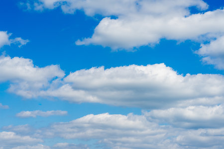 Skyscape with cumulus clouds in white and gray and a clear deep blue sky in the summerの写真素材