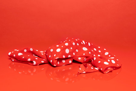 A Red and white dotted scarf against a red backgroundの写真素材