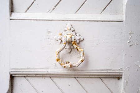 A Close up of a white worn vintage door and handle and knocker