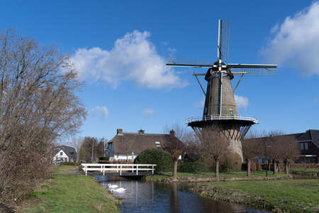 Bergambacht The Netherlands, 26 February 2021, Windmill Den Arend dating from 1869 in a farm landscape with waterのeditorial素材