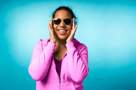 Young attractive mixed race woman with sunglasses in a blue backgroundの写真素材