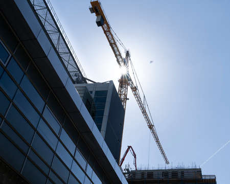 Construction site with tower crane for lifting building materials and the sun in a blue skyの写真素材