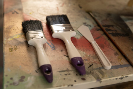 Two Paint brushes and painters knife lying ready for use on an artist table in an atelierの写真素材