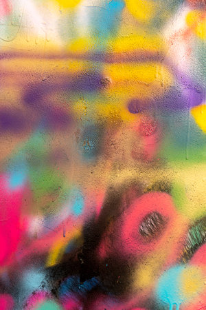 Some colorful and splattered spray paint graffiti over a cracked surface or concrete wall wiyh many colorsの写真素材
