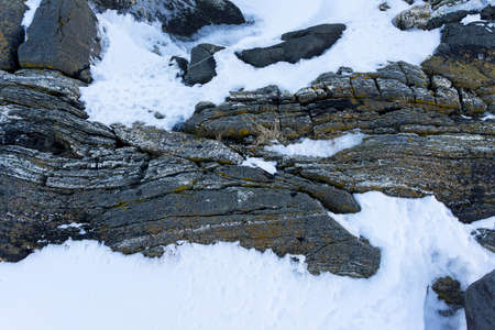 Granite layered rocks covered with snow in the arctic , Close up view from above