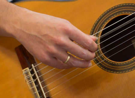 A female human hand playing an acoustic guitar strumming the stringsの写真素材