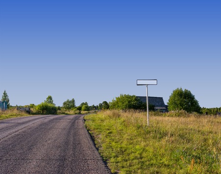 Road sign on a background of field and village houses.の写真素材
