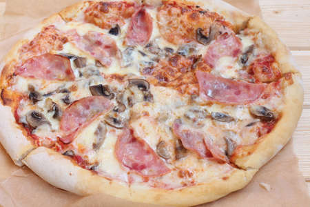pizza with ham and mushrooms on paperの写真素材