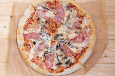pizza with ham and mushrooms on paperの写真素材