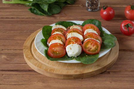 caprese salad in a white plate on a wooden tableの写真素材