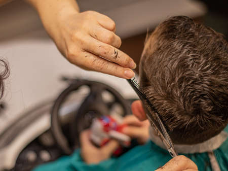Little boy in the barbershop machine haircut.