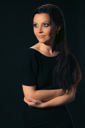portrait of a beautiful woman in a black dress on a dark background in the studioの写真素材