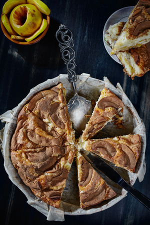 Charlotte with apples and cinnamon chopped in the baking dish on a wooden table, close-up, top view, vertical.の写真素材