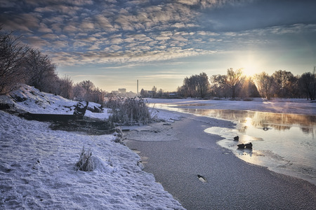 Sunrise on the river in winter. Dramatic Sky, ducks in the water.の写真素材