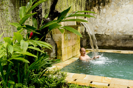 Young man in the pool in a luxury villa.の写真素材