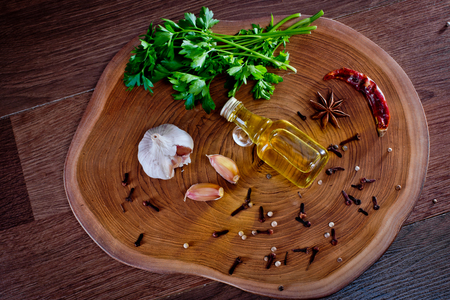 Top view of bottle with olive oil with spices on a wooden background, cloves of garlic and parsley. Backgrounds for the kitchen.の写真素材