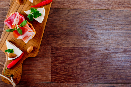 Top view on bruschetta sandwiches with jamon, cheese and green sprouts on a wooden board.の写真素材