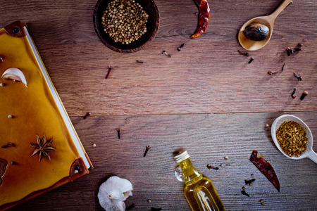 Top view on wooden background with spices, olive oil in bottle, garlic, papper chilli and note book. Backgrounds for the kitchen. Close-up.の写真素材