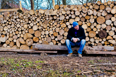 A man is a woodcutter sitting near a pile of firewood.の写真素材