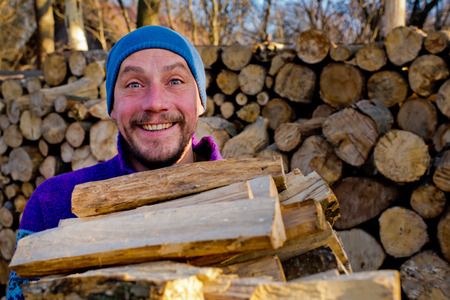 The woodcutter holds firewood in hand.の写真素材