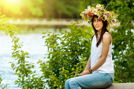 Portrait of a beautiful brunette girl in a wreath of flowers.の写真素材