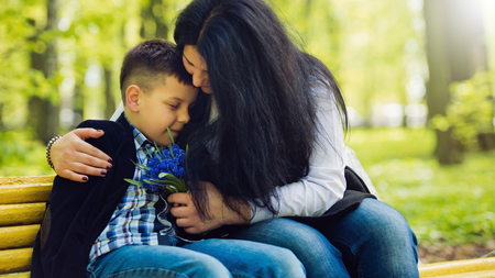 The son gives his mother a fresh bouquet of blue muscari flowers on a bench in the park. Family photo session.の写真素材