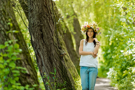 The brunette girl in a wreath on an alley in the forest.の写真素材