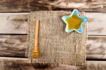 Honey in plate with wooden chopstick for honey on wooden background. Top view.の写真素材