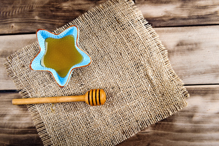 Honey in plate with wooden chopstick for honey on wooden background. Top view.の写真素材