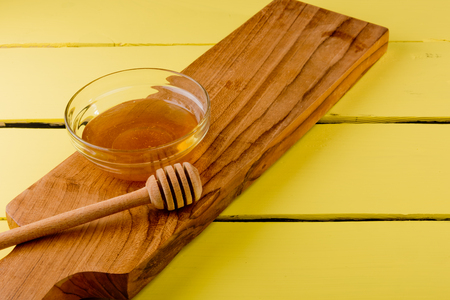 Honey in plate with wooden chopstick for honey on wooden background. の写真素材