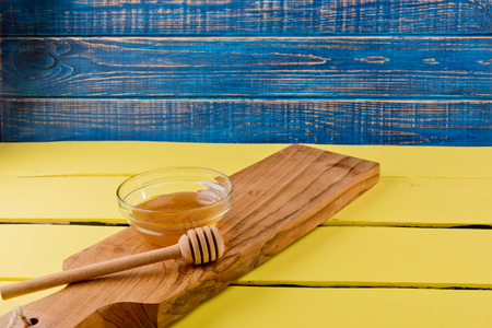 Honey in plate with wooden chopstick for honey on wooden background. の写真素材