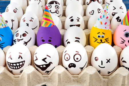 Eggs with drawn cartoon faces in tray.の写真素材