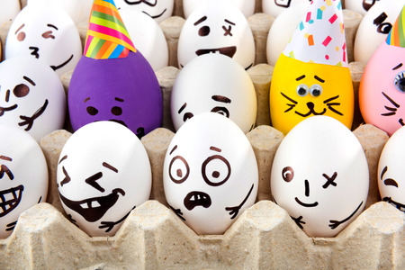 Eggs with drawn cartoon faces in tray.の写真素材