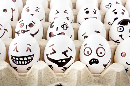 Eggs with drawn cartoon faces in tray.の写真素材