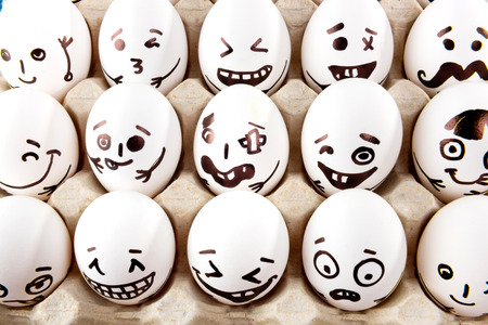Eggs with drawn cartoon faces in tray.の写真素材