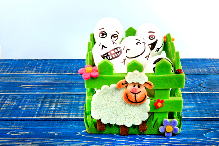 Funny easter eggs with different funny faces in the basket on white and blue background.の写真素材