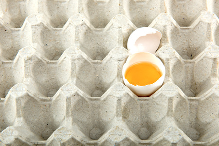 Chicken egg is half broken in egg tray. Close up.の写真素材