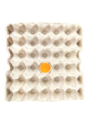 Chicken egg is half broken in egg tray on white background.の写真素材