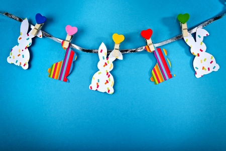 Garland with handmade Easter bunnies on blue background. Top view. Easter postcard.の写真素材
